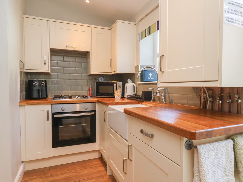 A kitchen with cabinets, stove, sink and appliances at Seashell Cottage