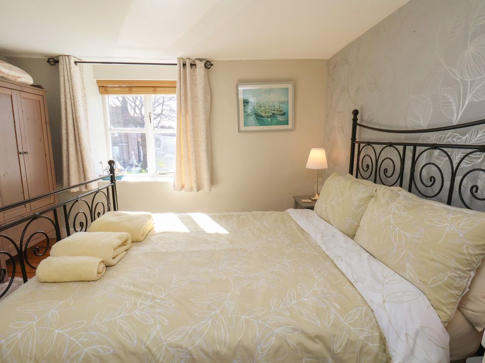 A bedroom with a bed and wardrobe at Seashell Cottage
