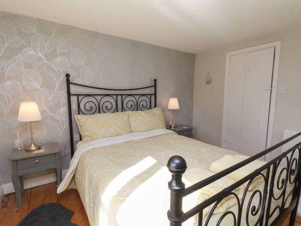 A bedroom with a bed and nightstand at Seashell Cottage in 