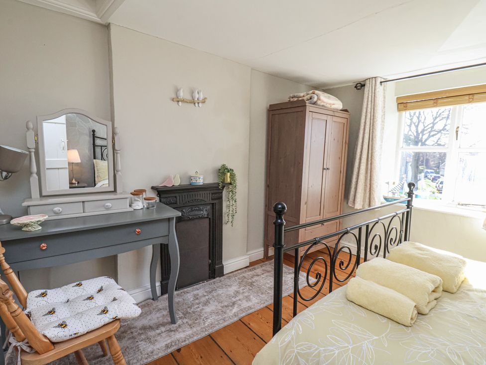 A bedroom with a bed, wardrobe, and a mirror at Seashell Cottage