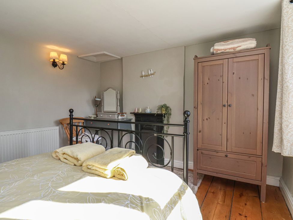 A bedroom with a bed and wardrobe at Seashell Cottage