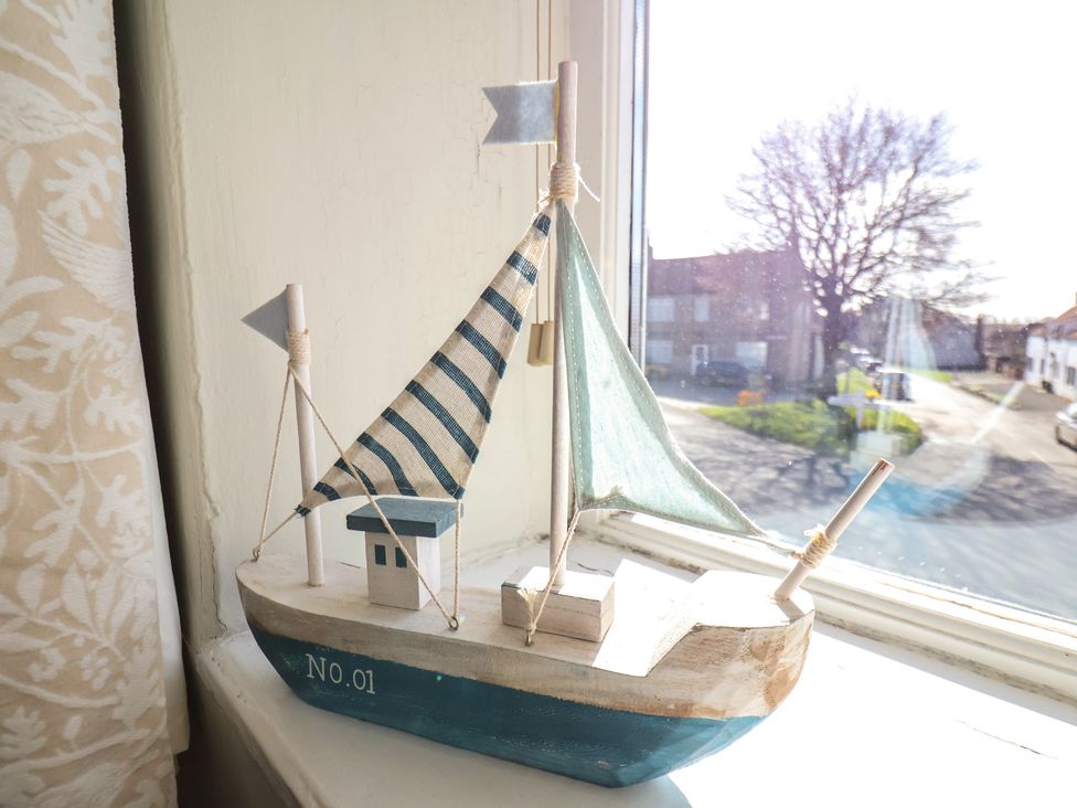 A sailboat decoration on a windowsill at Seashell Cottage
