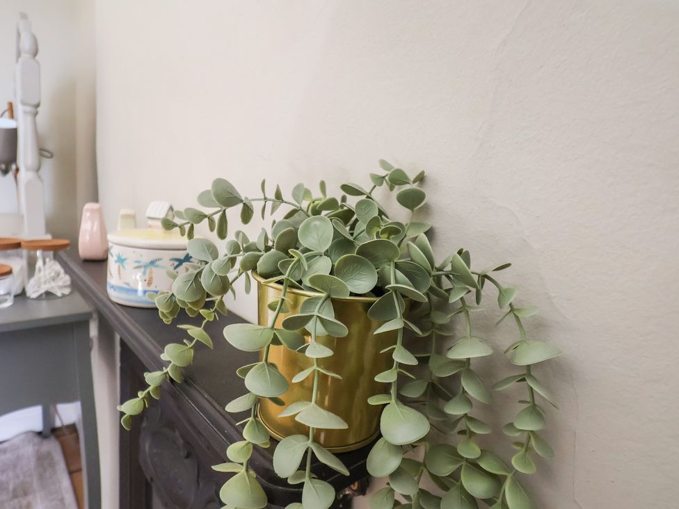 A plant in a gold pot on a table in Seashell Cottage