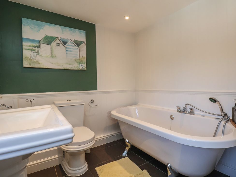 A bathroom with a bathtub, toilet, and sink at Seashell Cottage