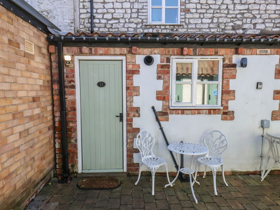 An outdoor area with a door and table with chairs at Seashell Cottage