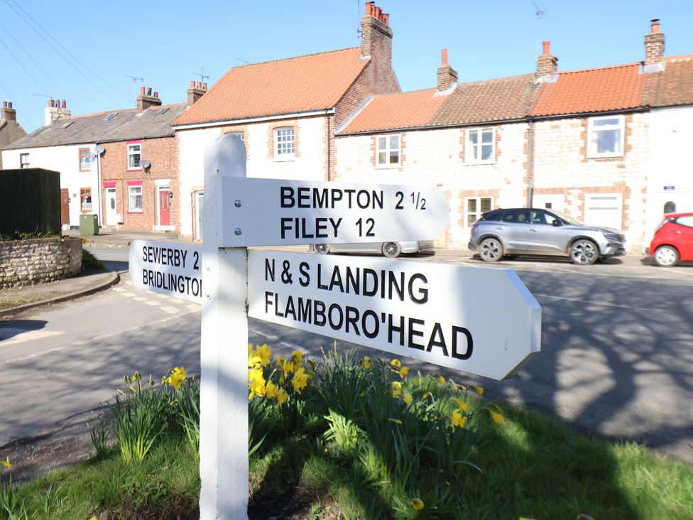 A signpost with distances to locations and houses at Seashell Cottage in 