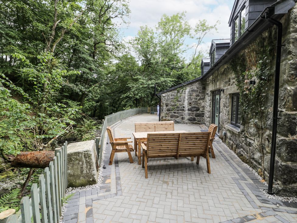 An outdoor patio with wooden furniture at Frongoch Old Power House in Dolgellau