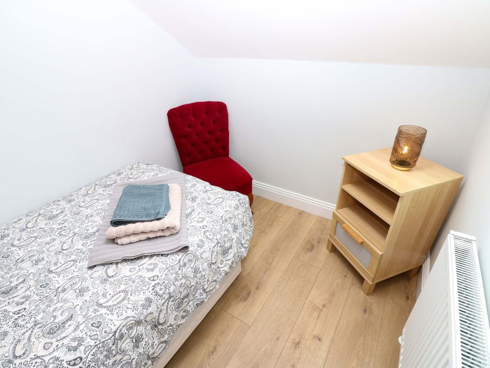A bedroom with a bed and a chair at 8 Percy Terrace in Whitburn