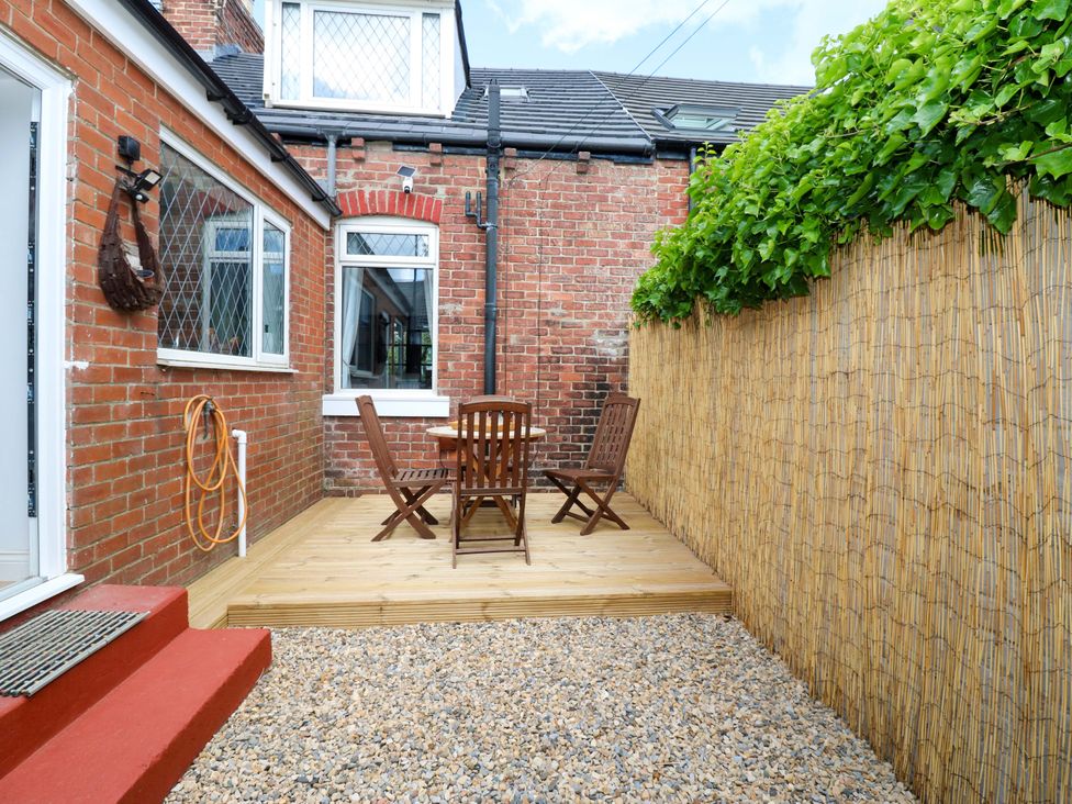 A garden with a wooden table and chairs at 8 Percy Terrace in Whitburn