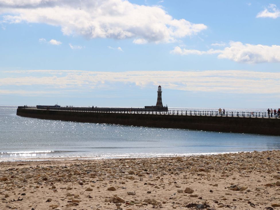 A beach with a lighthouse and pier at 8 Percy Terrace in Whitburn