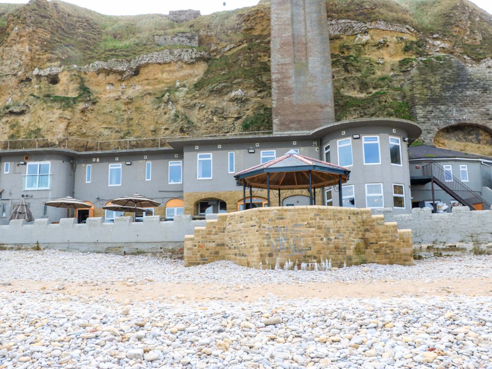 An outdoor area with a building and umbrellas at 8 Percy Terrace in Whitburn