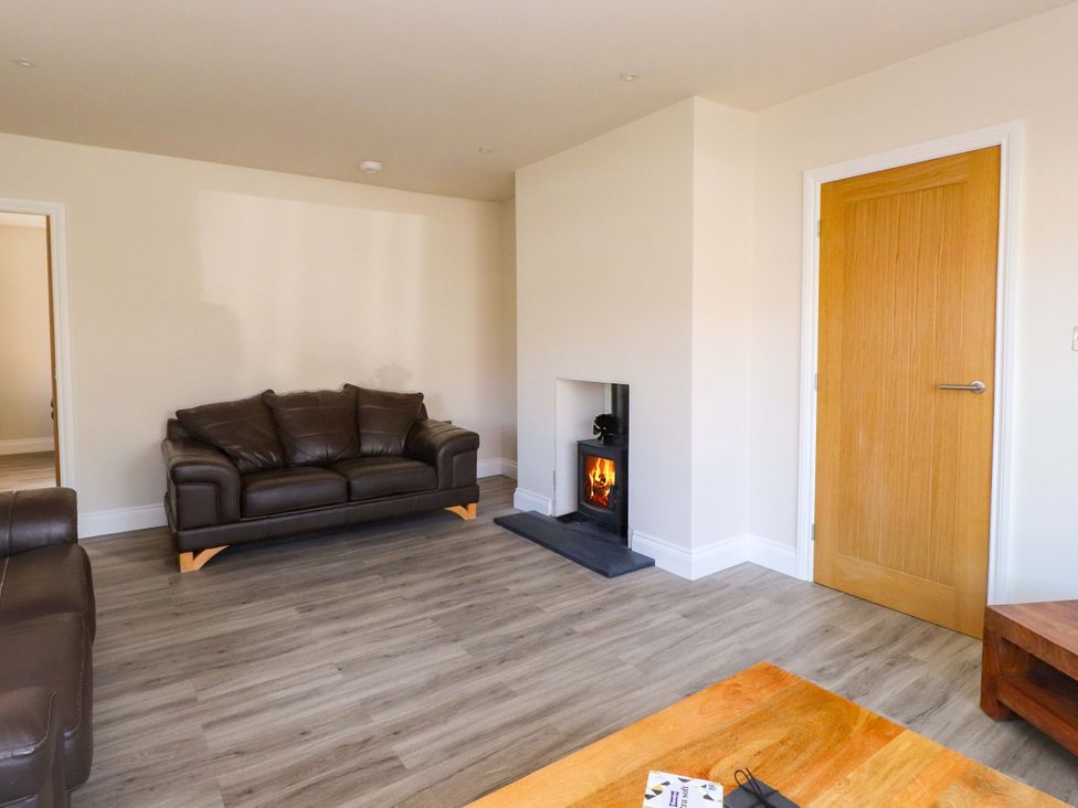 A living room with a brown sofa and a fireplace at Morannedd in Morfa Nefyn