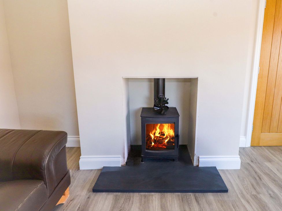 A living room with a fireplace and door at Morannedd in Morfa Nefyn