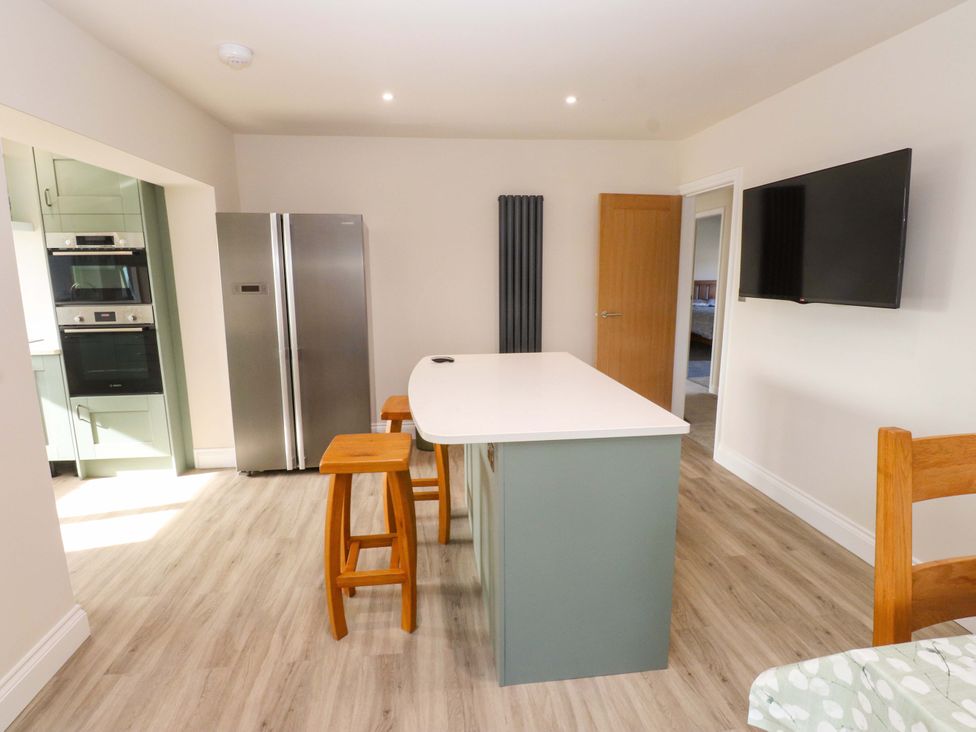 A kitchen with an island and stools at Morannedd in Morfa Nefyn