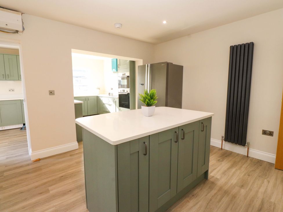 A kitchen with cabinets and a refrigerator at Morannedd in Morfa Nefyn