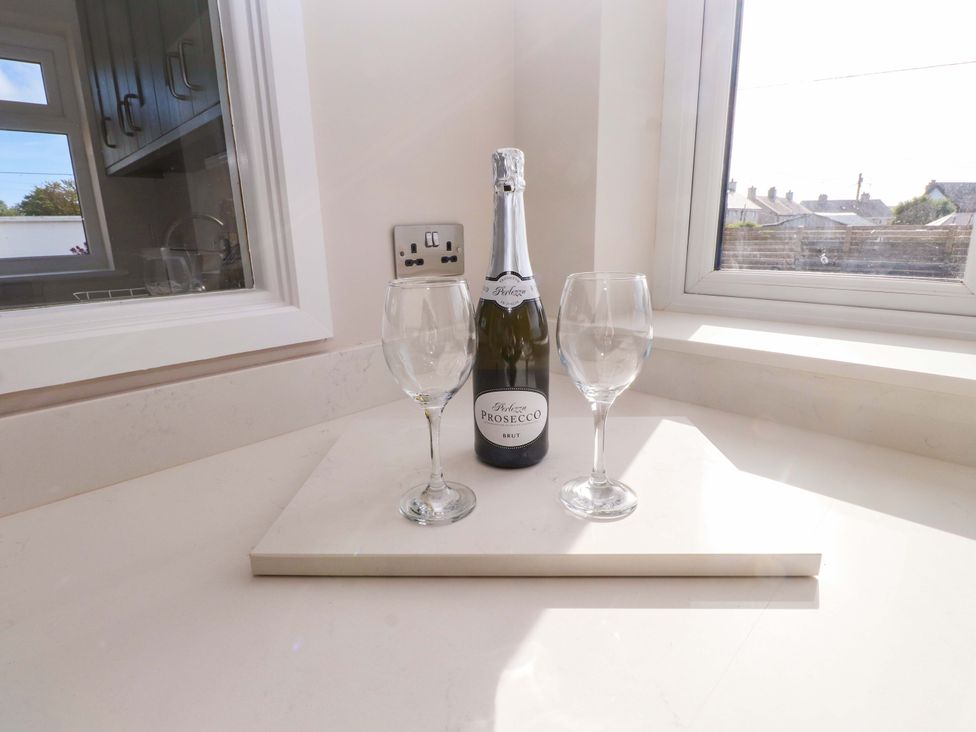 A bottle of Prosecco and two glasses on a countertop at Morannedd Morfa Nefyn