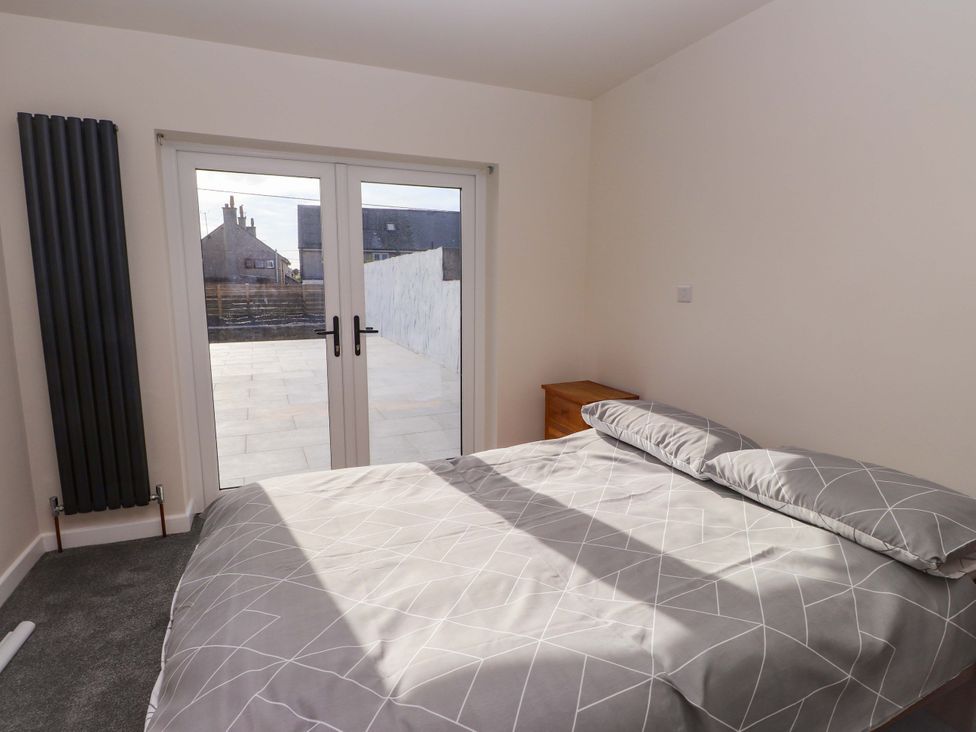 A bedroom with a bed and double doors at Morannedd in Morfa Nefyn