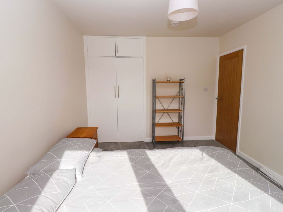 A bedroom with a bed, shelf, and wardrobe at Morannedd in Morfa Nefyn