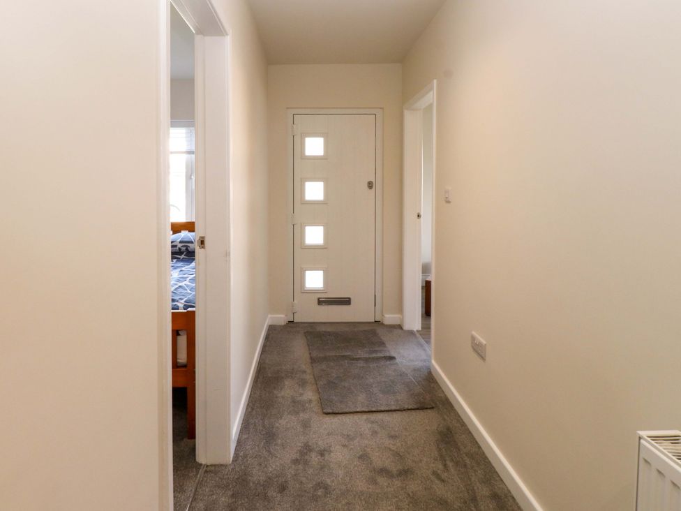 A hallway with a door and a view of a bedroom at Morannedd Morfa Nefyn