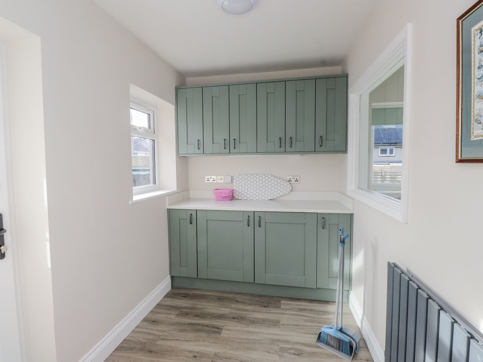 A utility room with cabinets and a window at Morannedd in Morfa Nefyn