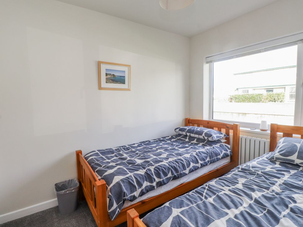 A bedroom with two beds and a window at Morannedd Morfa Nefyn