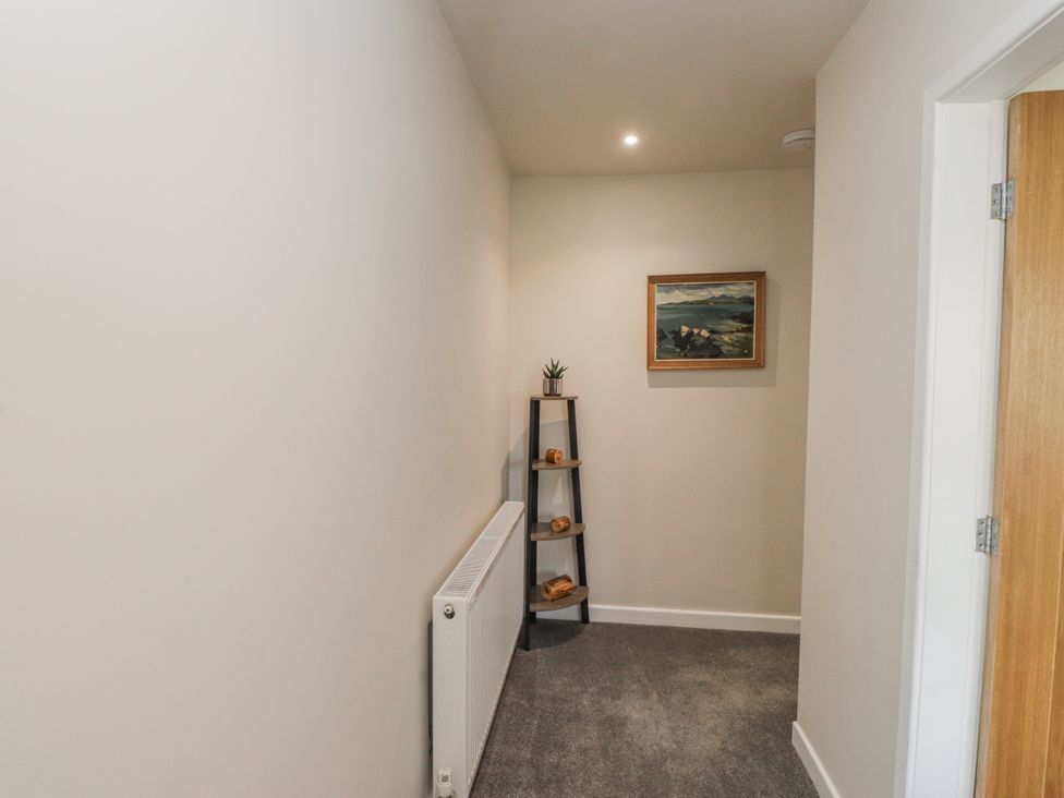 A hallway with a shelf and painting at Morannedd in Morfa Nefyn