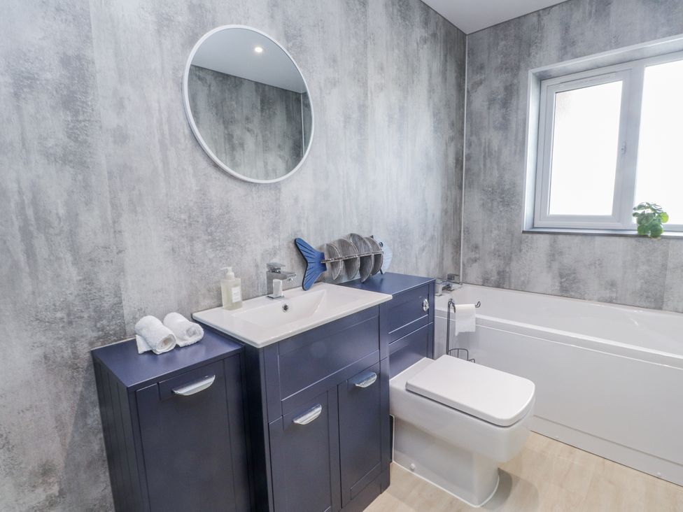 A bathroom with a sink, toilet, and bath tub at Morannedd in Morfa Nefyn
