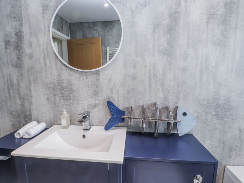 A sink with a mirror and decorative fish at Morannedd in Morfa Nefyn
