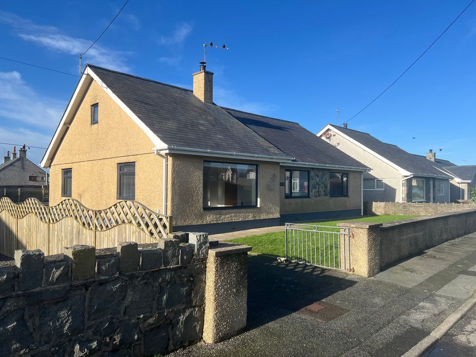 A view of a house with a fence and garden at Morannedd in Morfa Nefyn