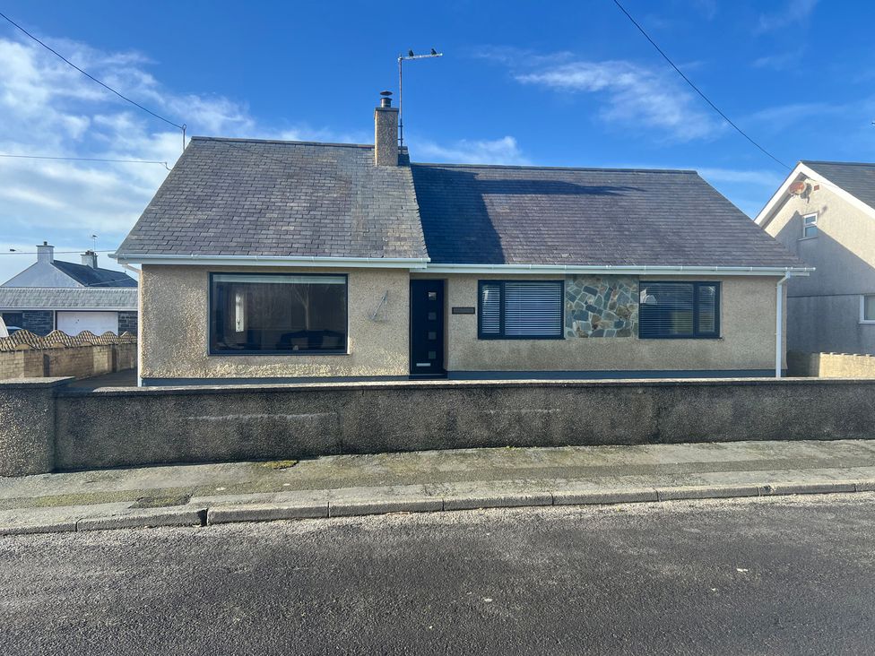A house with a stone feature wall and large front window at Morannedd in Morfa Nefyn