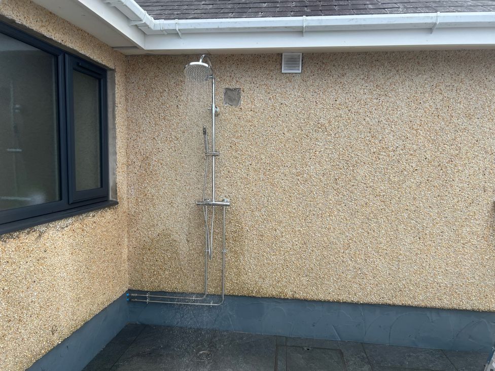 An outdoor shower on a textured wall at Morannedd in Morfa Nefyn