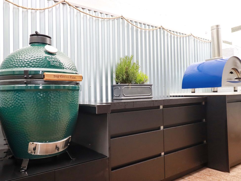An outdoor kitchen with a Big Green Egg and a pizza oven at Beach View House in Newquay