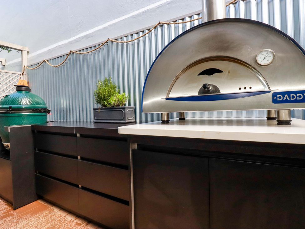An outdoor kitchen with a pizza oven and barbecue grill at Beach View House in Newquay