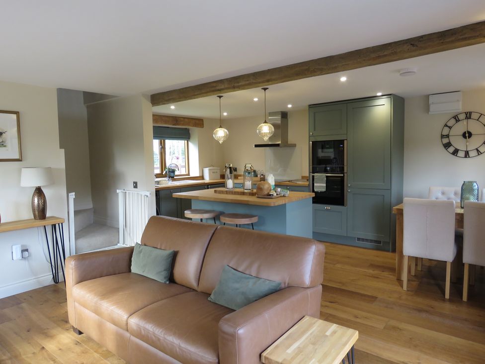 A kitchen with a sofa and kitchen island with stools at The Cartshed in Defford
