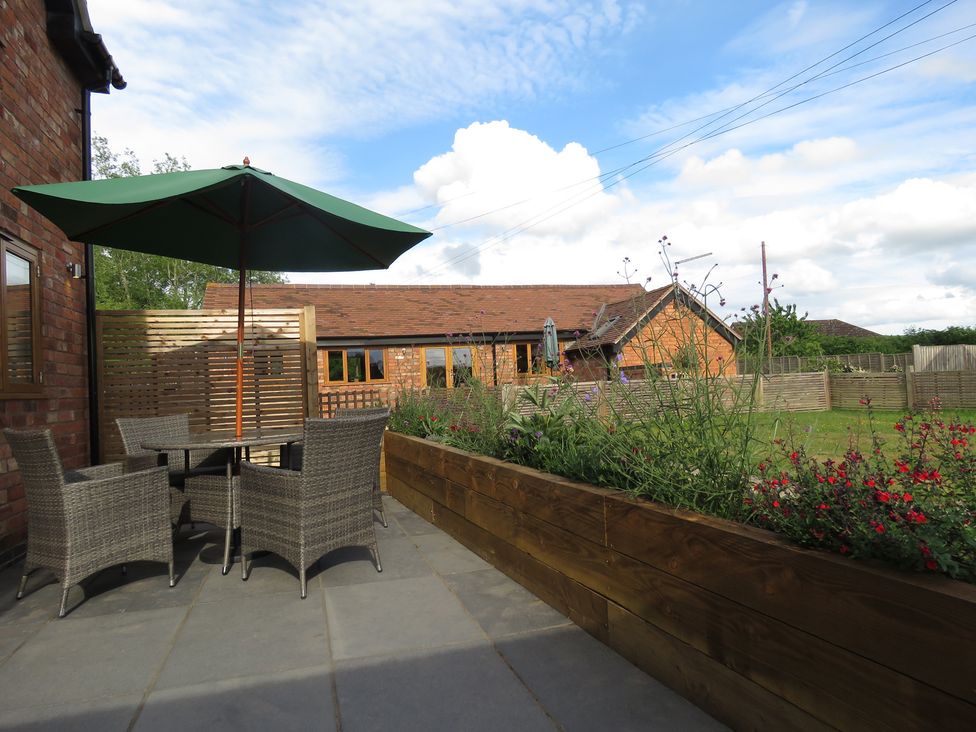 A garden with a table and chairs under an umbrella at The Cartshed in Defford