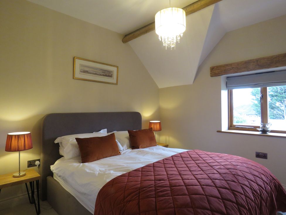A bedroom featuring a bed, nightstand, and window at The Cartshed in Defford