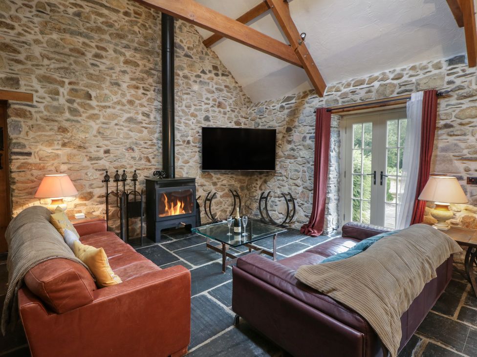 A living room with a sofa, coffee table, and fireplace at St Dogwells Barn near Wolfscastle