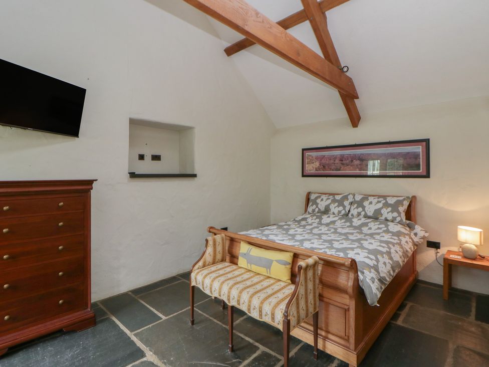 A bedroom with a bed, dresser and tv at St Dogwells Barn near Wolfscastle