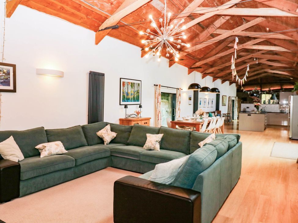 A living room with a green sofa and dining area at Halshanger Barn in Newton Abbot