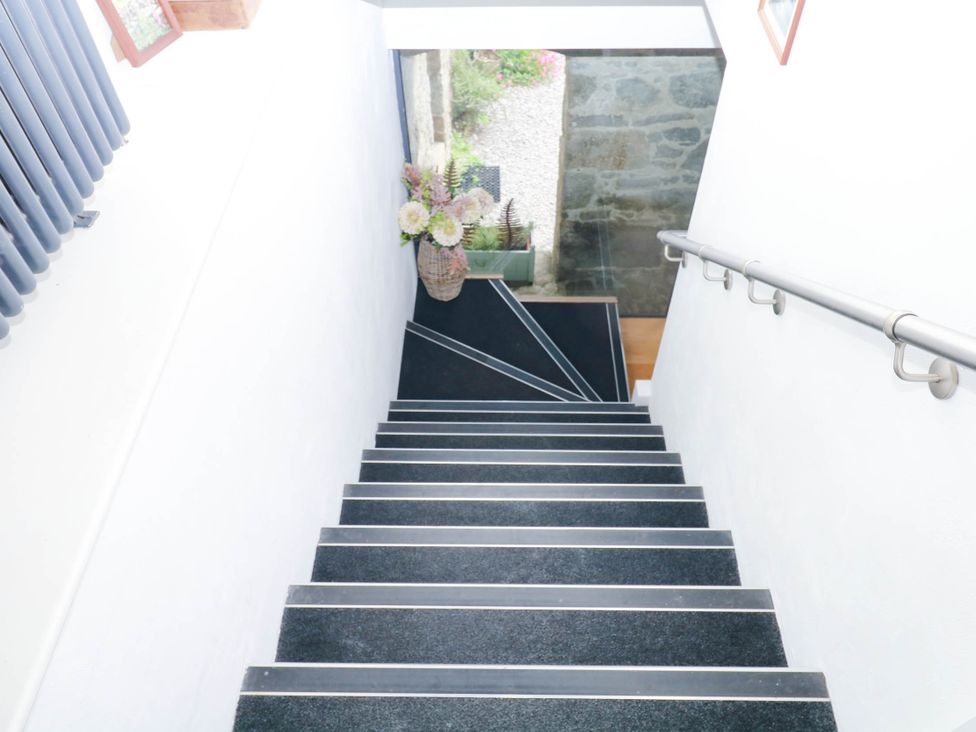 A staircase leading to a door with a flower arrangement at Halshanger Barn Newton Abbot
