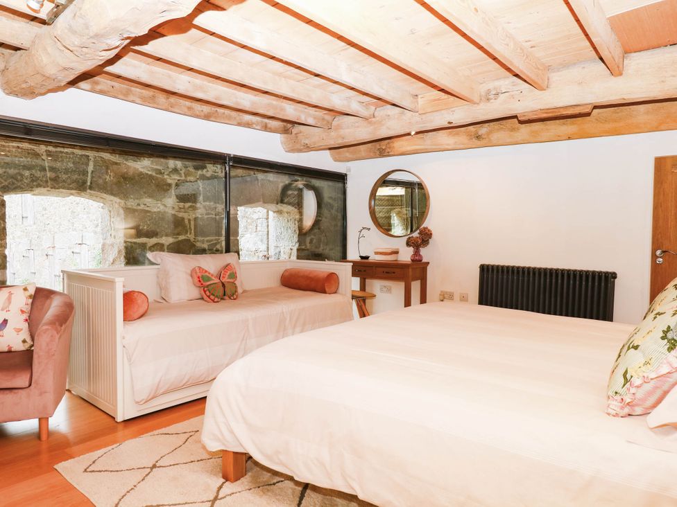 A bedroom with a bed and a sofa at Halshanger Barn in Newton Abbot