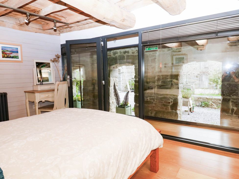 A bedroom with furniture and views to an outdoor area at Halshanger Barn in Newton Abbot