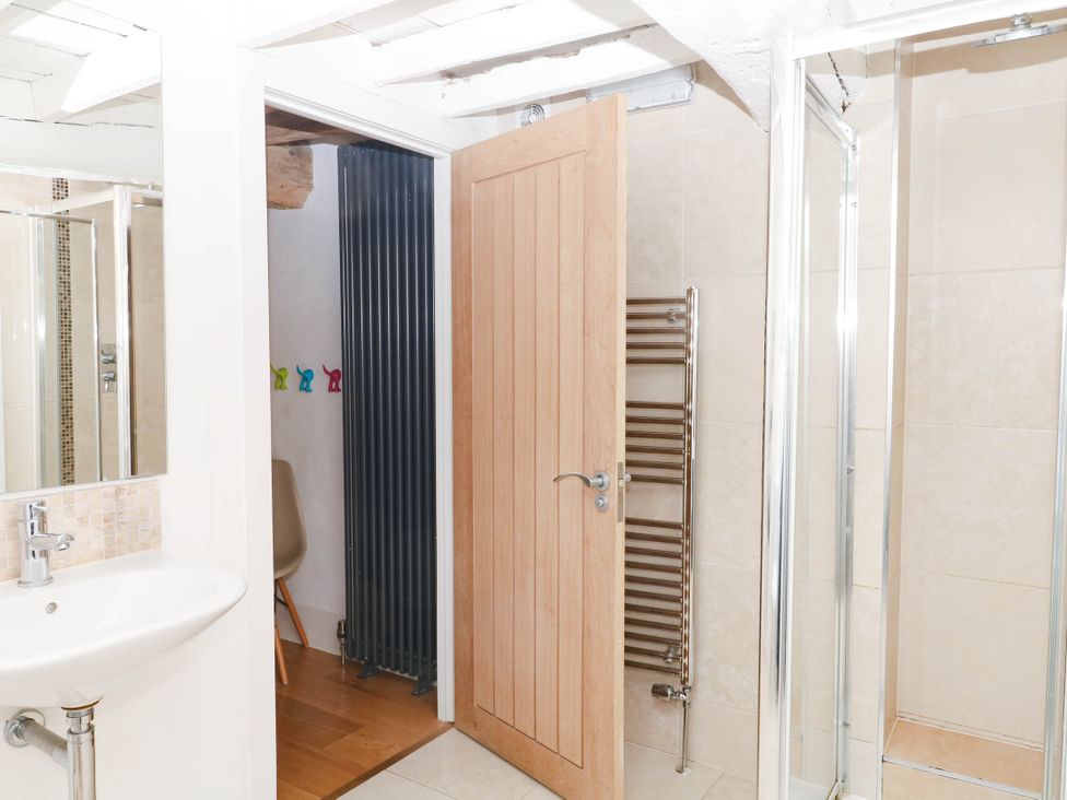 A bathroom with a sink, mirror, and shower at Halshanger Barn in Newton Abbot