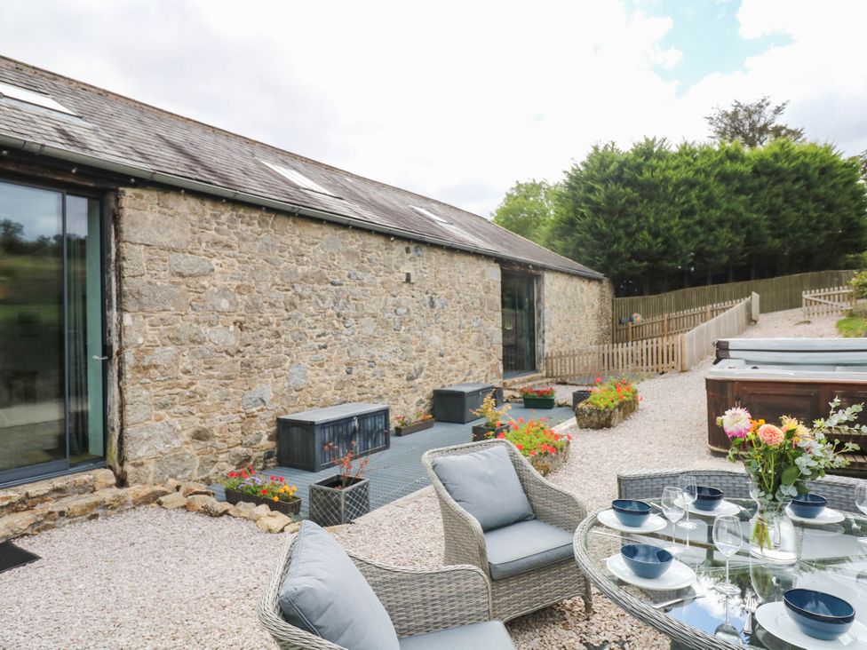 An outdoor area with a glass table and chairs at Halshanger Barn in Newton Abbot