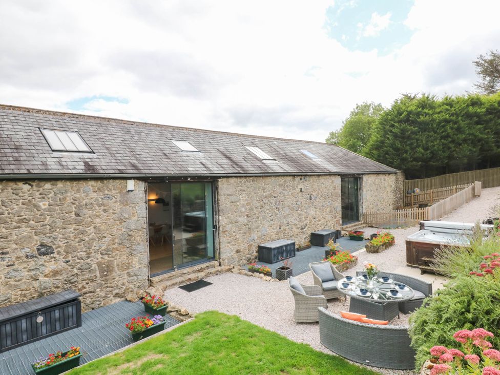 A garden area with stone building and outdoor furniture at Halshanger Barn in Newton Abbot