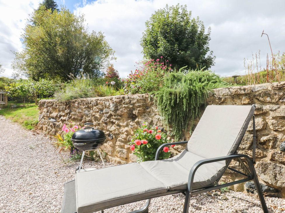 A lounge chair and grill in a garden at Halshanger Barn Newton Abbot