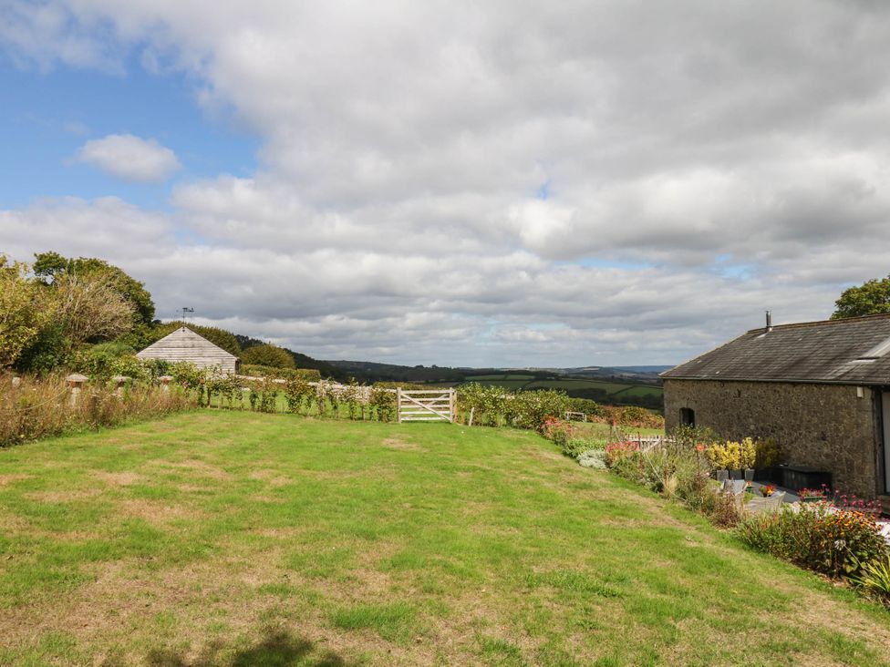 A garden with a gate and flower beds at Halshanger Barn in Newton Abbot