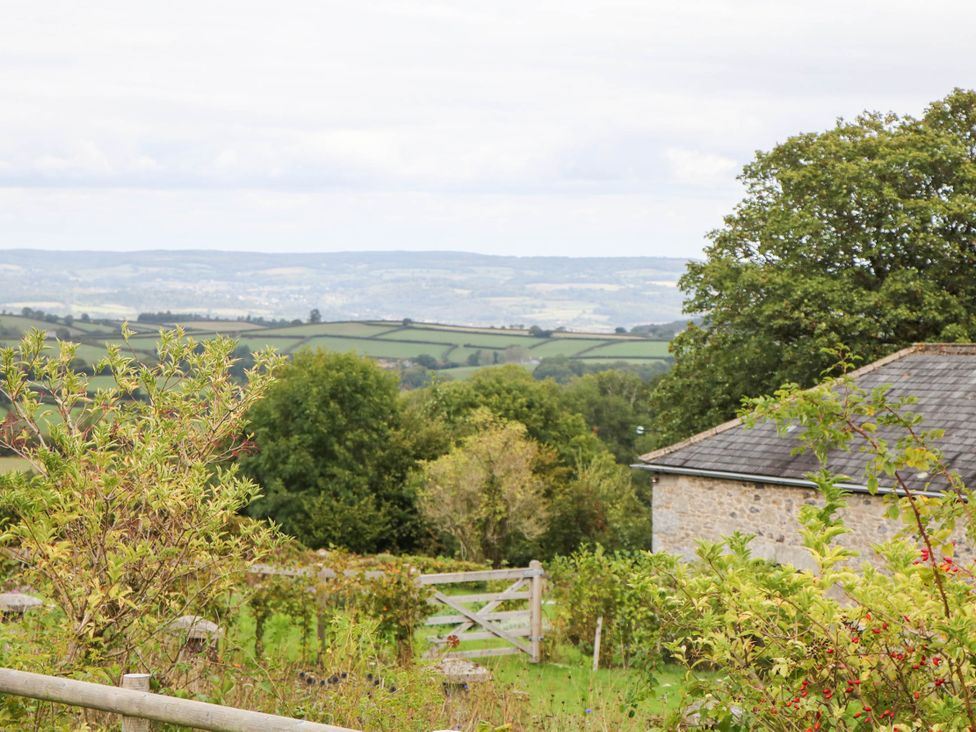 A view of fields and hills with a building and trees at Halshanger Barn in Newton Abbot