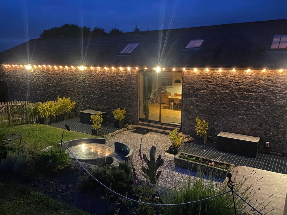 A garden with plants and seating at Halshanger Barn near Ashburton
