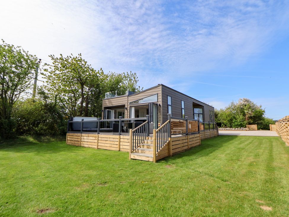 An outdoor view of a house with a deck and grass at The Lodge @ Racecourse House Babell near Holywell